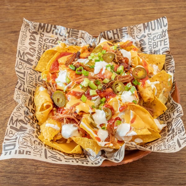 William's Barbecue pulled pork nachos with cheese sauce, sour cream, jalapeños, and green onions.
