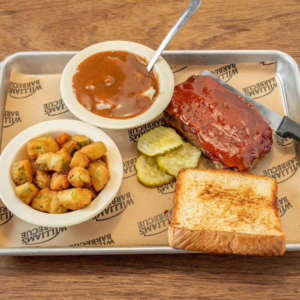 William's Barbecue meatloaf with gravy, fried okra, pickles, and Texas toast on a metal tray.