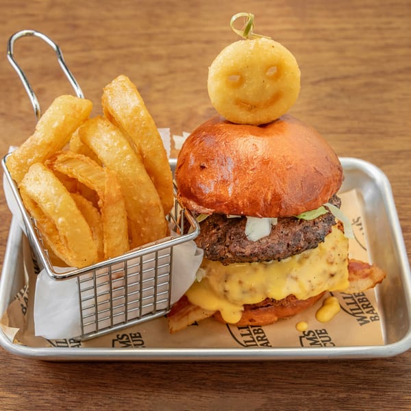 William's Barbecue burger with bacon, cheese, lettuce, onions, and a smiley face potato puff, with onion rings.