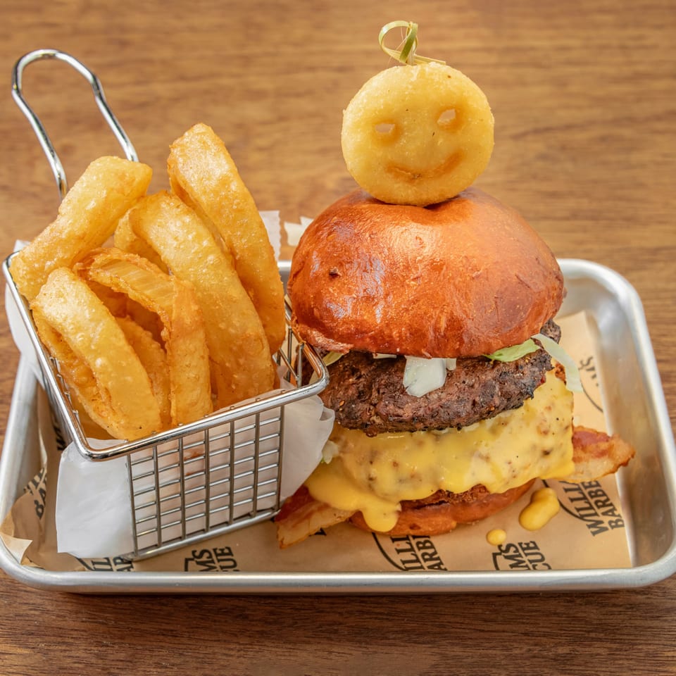 William's Barbecue burger with bacon, cheese, lettuce, onions, and a smiley face potato puff, with onion rings.