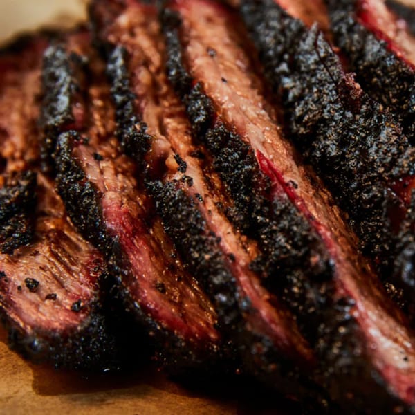 Close-up of William's Barbecue sliced brisket with a dark, peppery bark and a pink smoke ring.